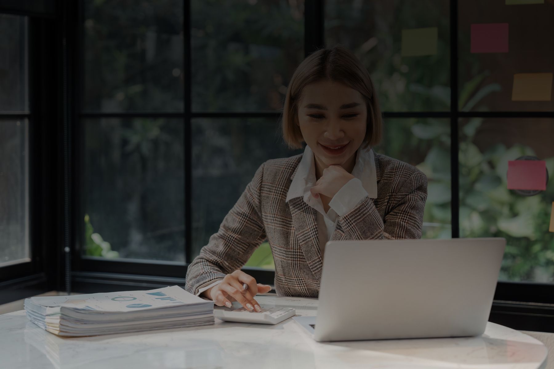 Asesora de MC Contadores Confiable utilizando una laptop y calculadora para agilizar trámites ante el SAT en CDMX a un cliente.